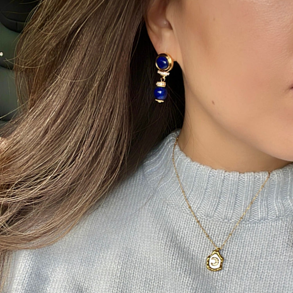 model wearing blue sweater and wearing blue lapis earrings with gold button detail 