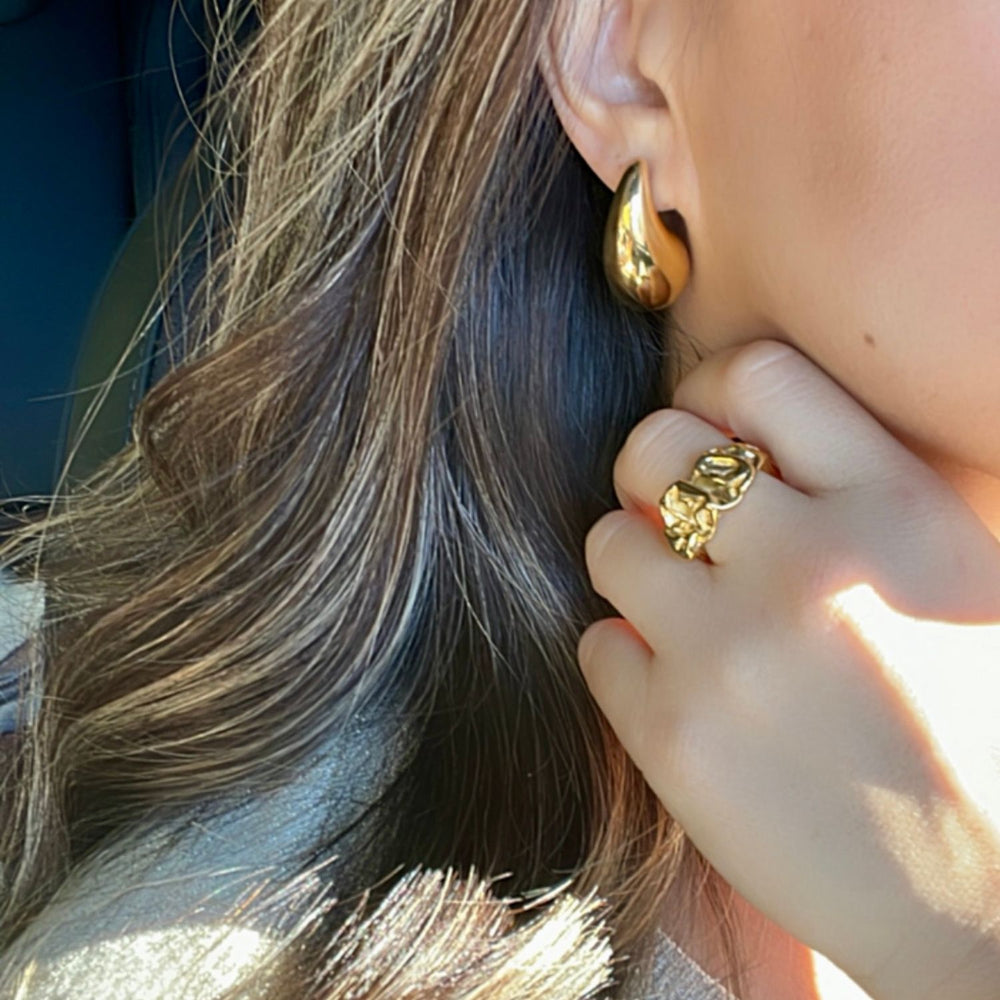 gold rain drop shaped earrings worn on a model showing the style along with a gold ring