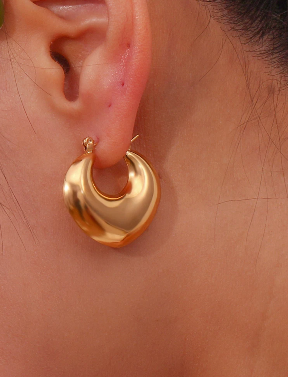 gold puffy abstract heart hoop earrings worn on model