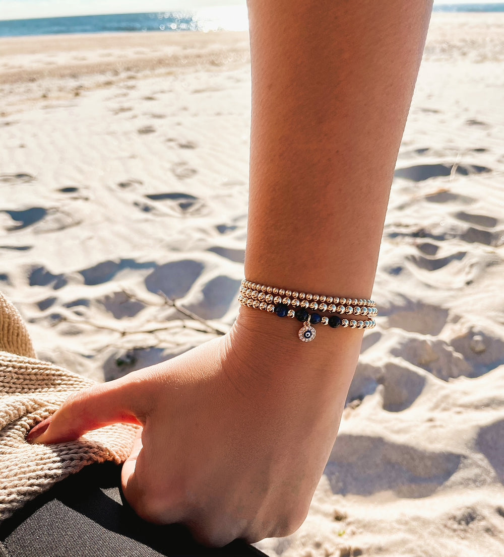 Olivia Le model at the beach wearing the beaded evil eye gold-filled bracelet stack with 3MM and 5MM gold-filled bracelet