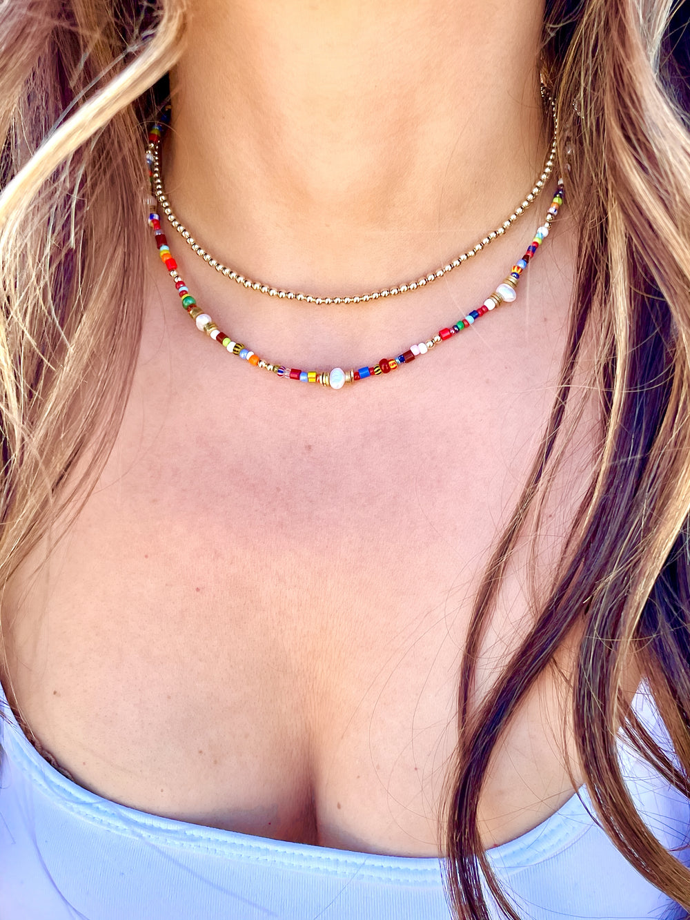 Olivia Le model wearing the jetsetter beaded necklace layered with the 3mm gold bubble bead necklace showcasing wearing a white tank top