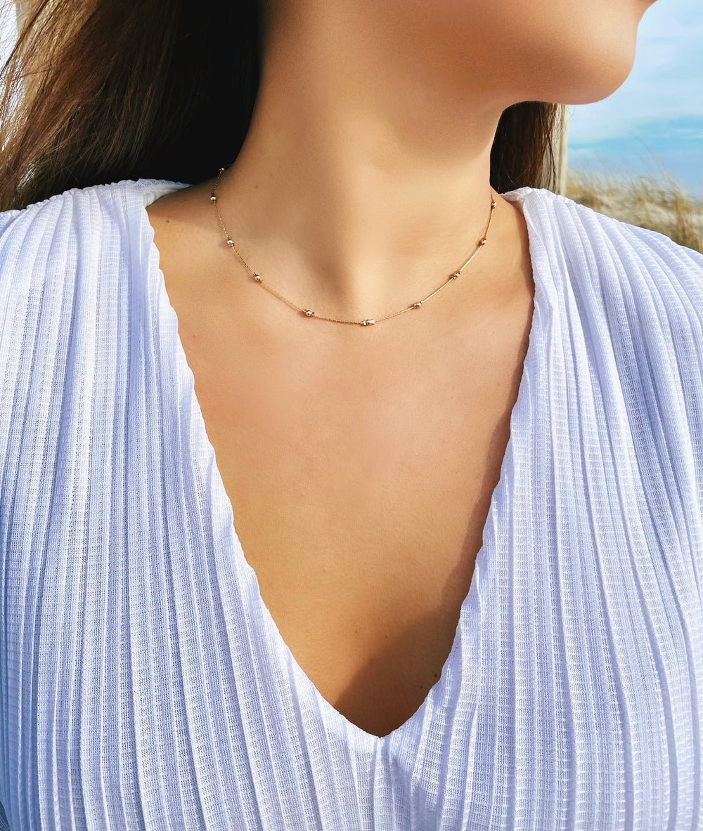 Olivia Le model wearing the Journey Golden Beaded Necklace and white top