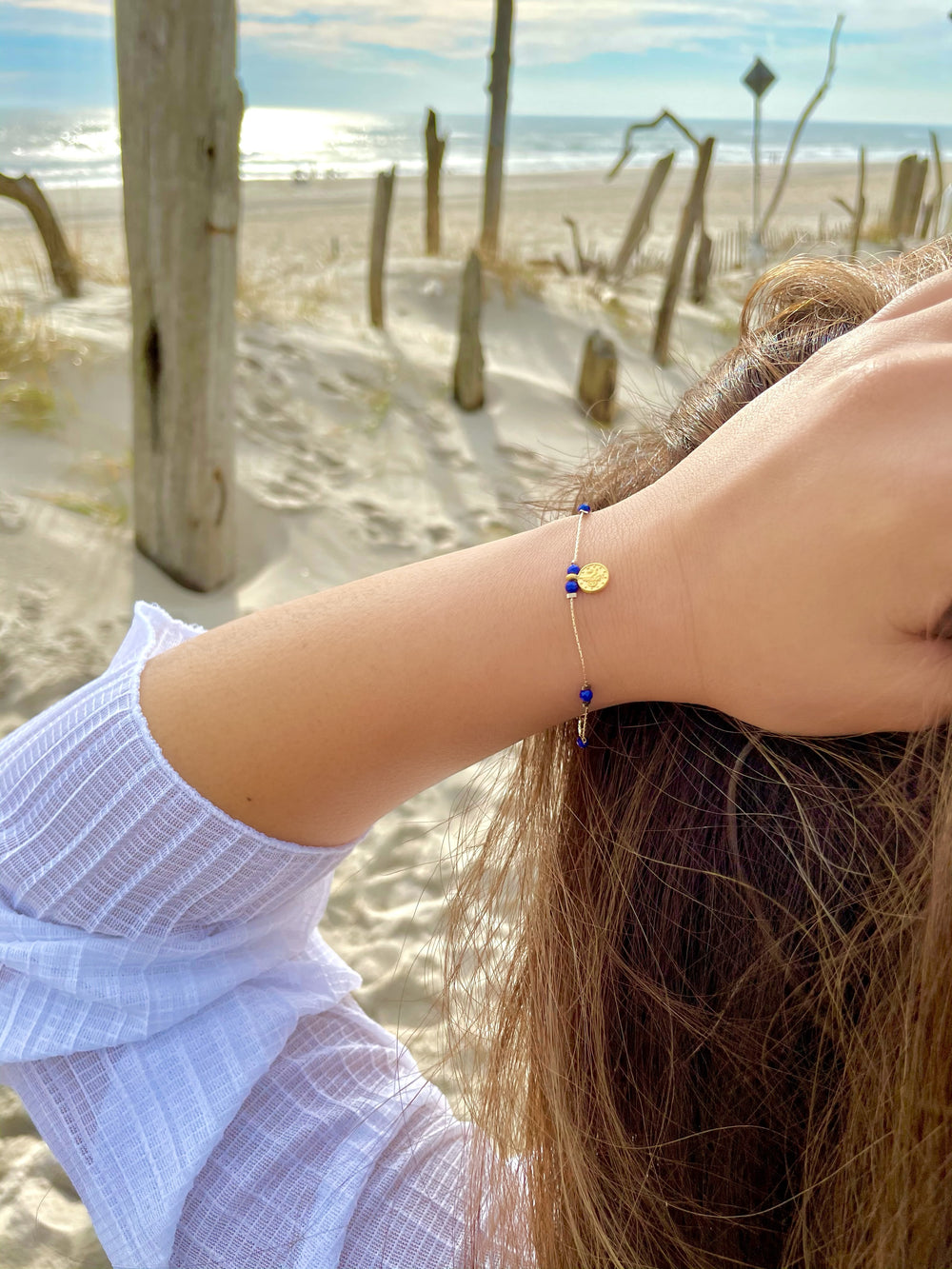 Olivia Le model at the beach wearing the Journey Lapis Lazuli Beaded Bracelet with Coin pendant