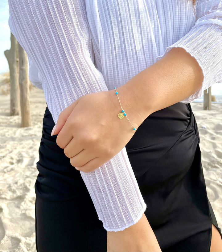 Olivia Le model wearing the Journey Turquoise Magnesite Beaded Bracelet with Coin pendant and white top