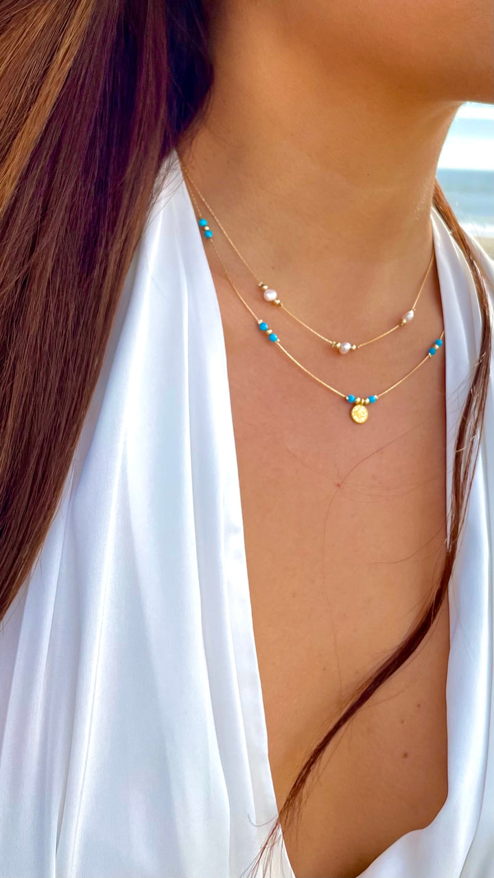 Olivia Le model wearing the Journey Turquoise Magnesite Beaded Necklace with Coin pendant and white top