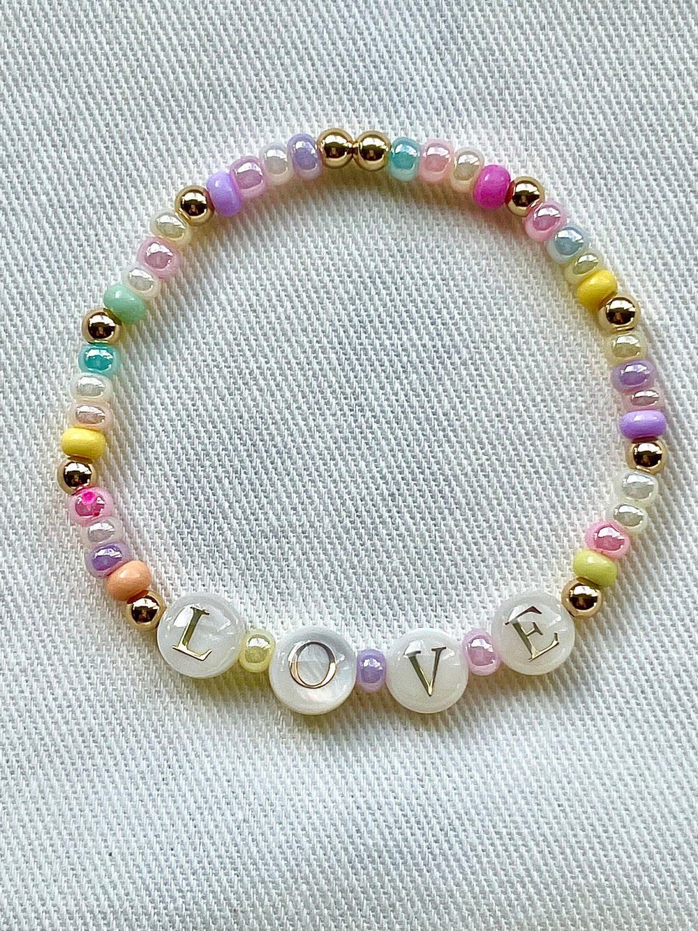 Olivia le love pearl beaded pastel bracelet shown on a cloth display