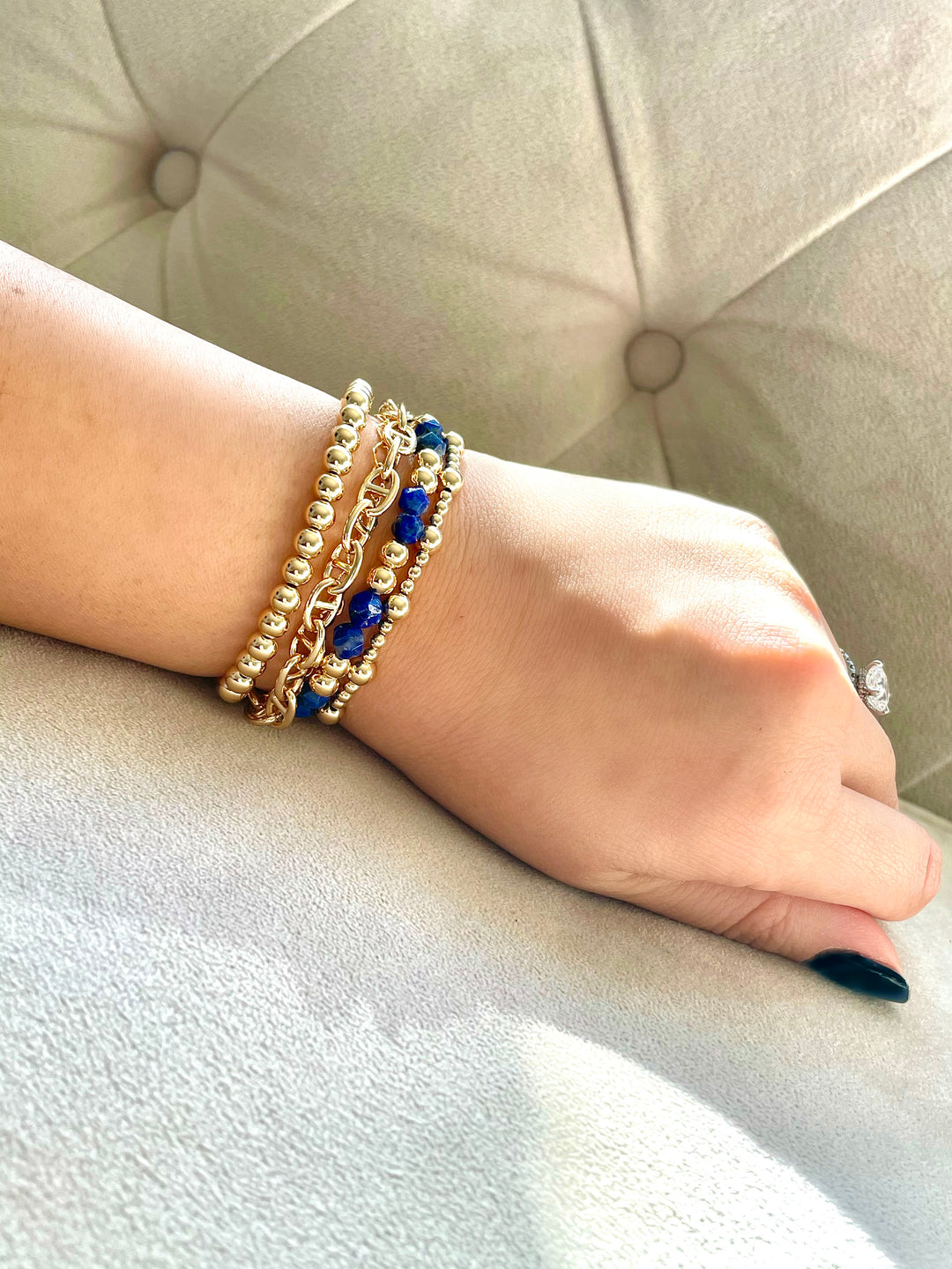 Gold bracelets layered on hand model showing multiple bracelets