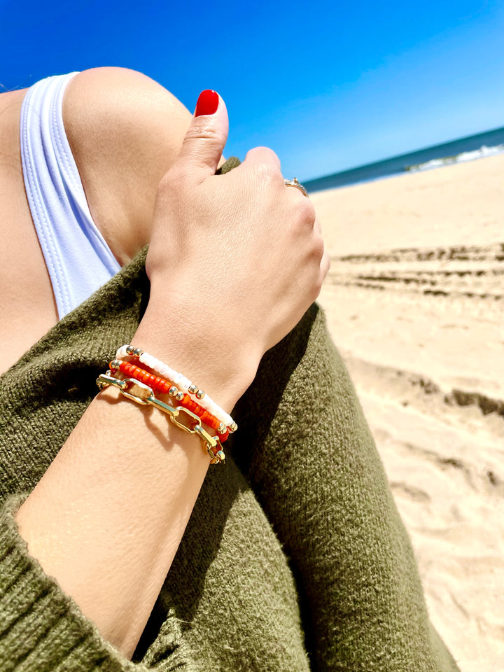 Olivia Le model wearing the mini flora coral bracelet with the mini harper pearl bracelet and showcasing with her hand on her shoulder to show the different looks of bracelets