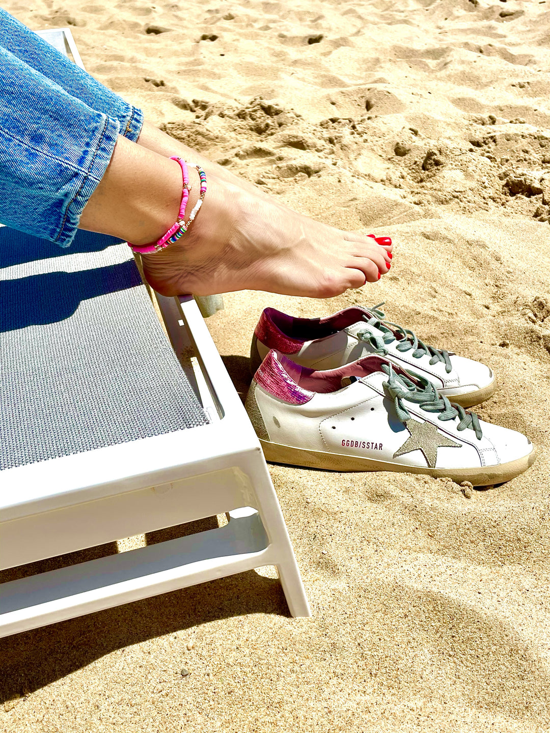 Olivia le model wearing the neon pearl anklet that has hot pink polymer clay beads with freshwater pearl charms and layered with the rio rainbow anklet barefoot on the beach 