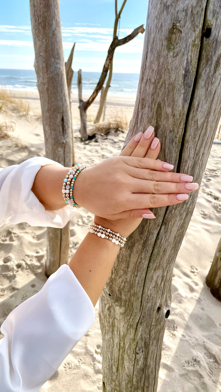 Olivia Le model at the beach wearing opal stack gold-filled bead bracelets