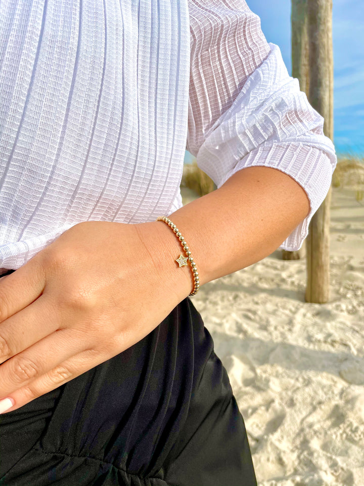 Olivia Le model at the beach wearing the Star Bright Pave Gold Bracelet