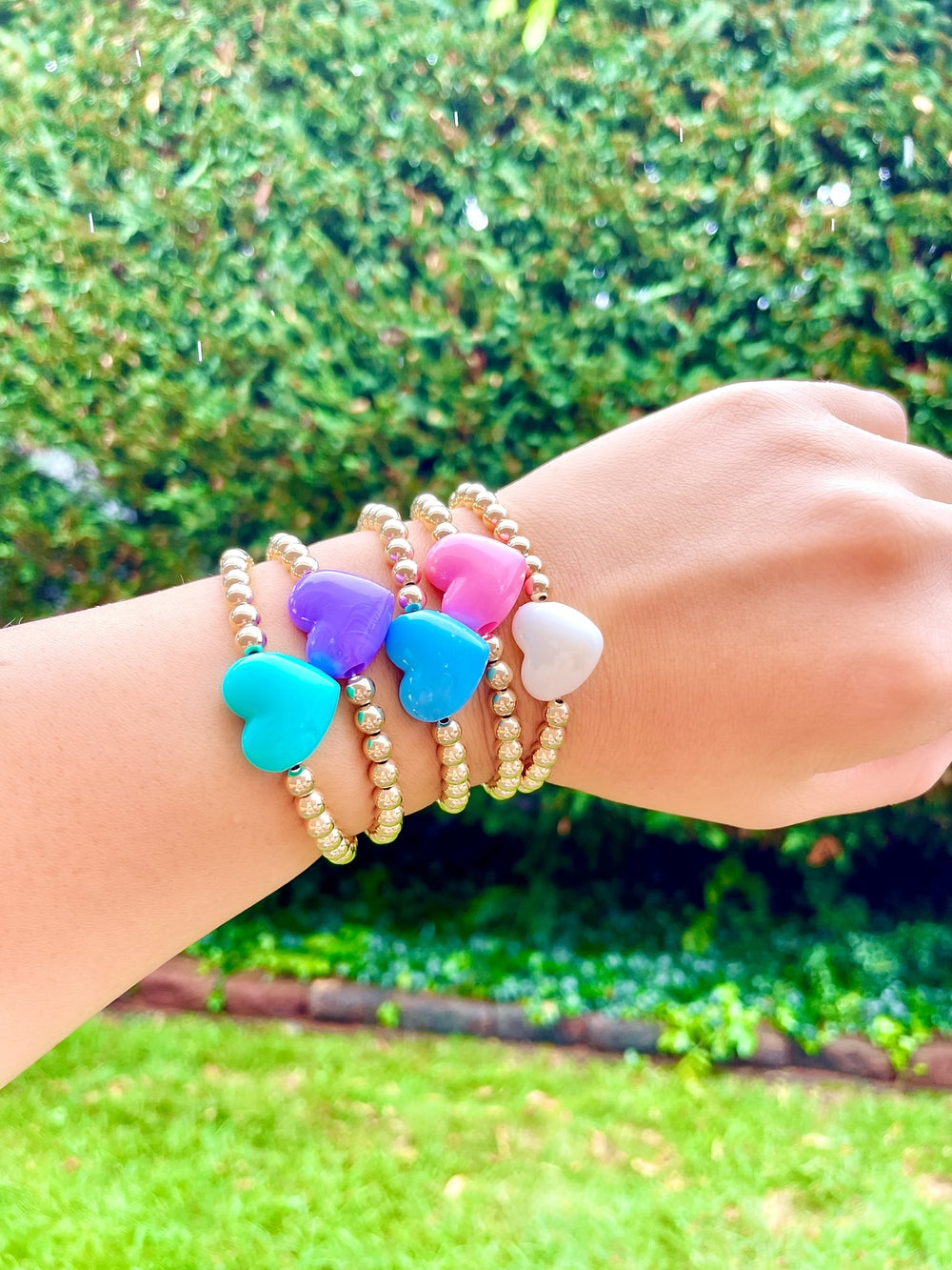Olivia le love heart bracelet on model showing all 5 colors of the puff love heart bracelet on wrist