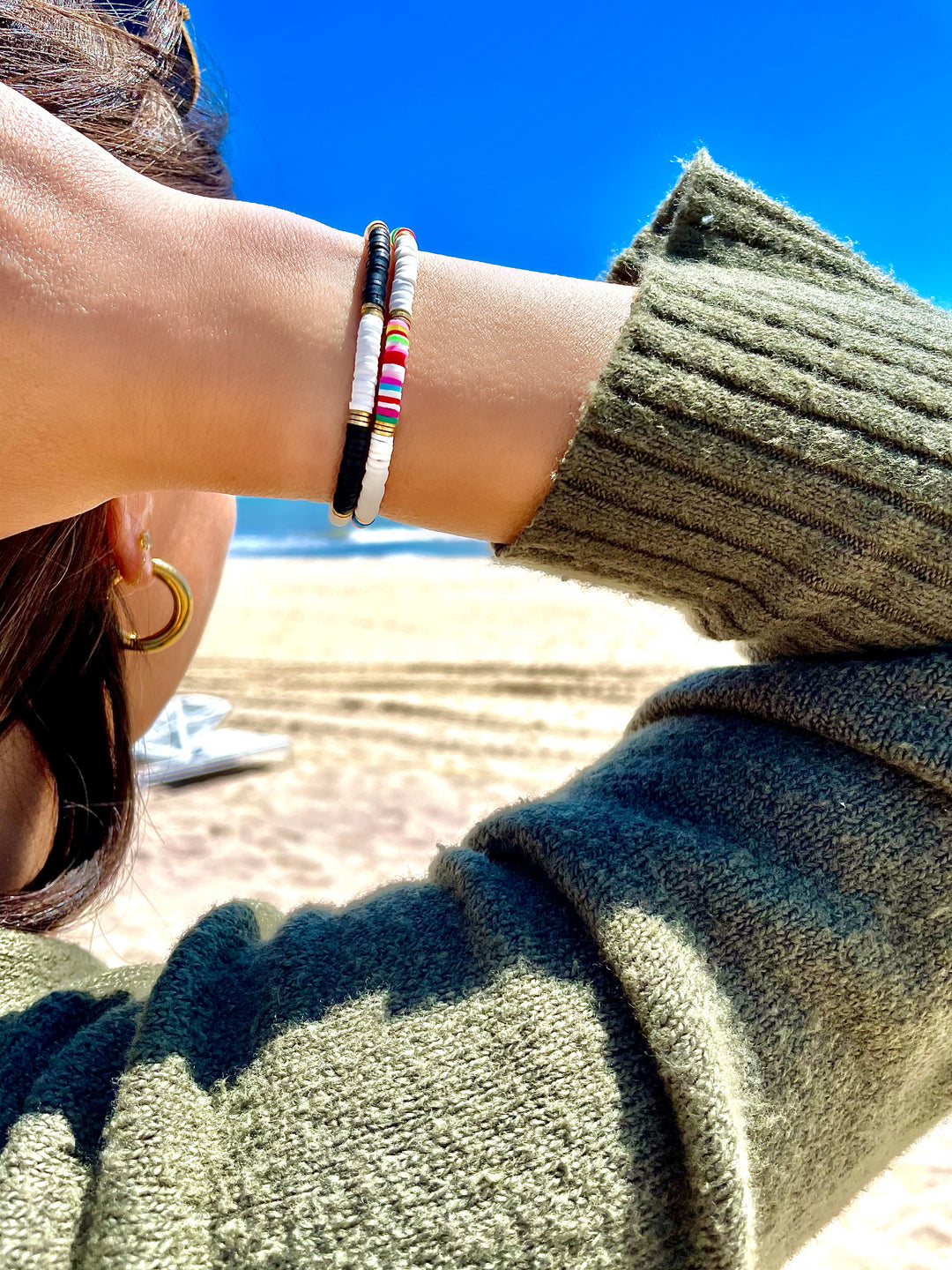Olivia le modeling seychelles bead bracelet which is shown in black and white polymer clay beads with gold plated brass discs worn layered with the rainbow seychelles bead bracelet