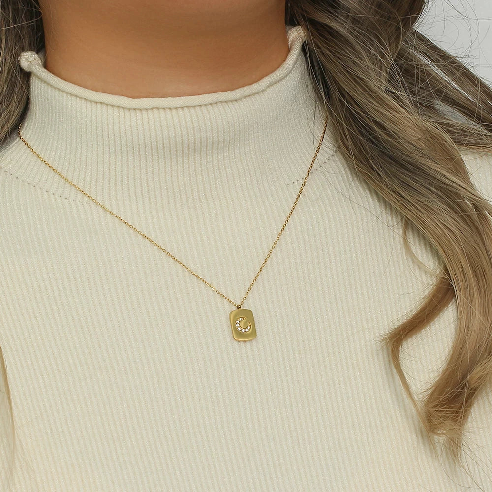 Model wearing a cream color turtle neck showing the necklace with the gold chain and crescent moon pendant
