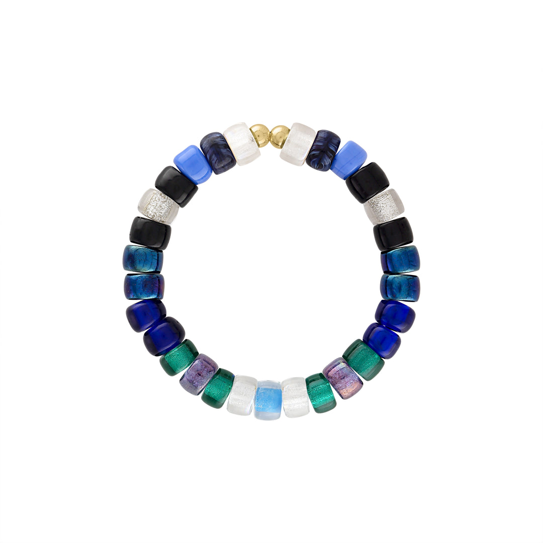 olivia le galaxy glass bead bracelet shown with cool blue toned glass czech beads with alternating patterns with multicolor beads shown in blues and black with green finished with gold filled beads on a stretch elastic bracelet