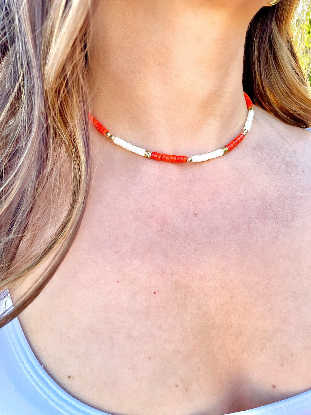 Olivia le model wearing kaia beaded necklace which consists of coral heishi beads and mother of pearl beads mixed with gold plated brass beads and gold filled round beads 