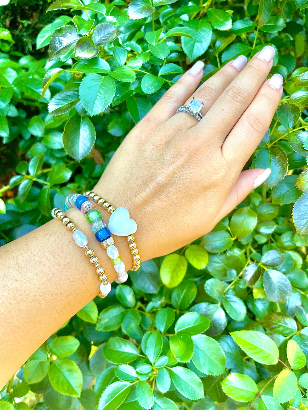 olivia le la perla bracelet on models hand showing the gold beaded bracelet with fresh water pearls beaded onto the stretch elastic bracelet shown with other beaded bracelets to showcase a layered bracelet look on hand