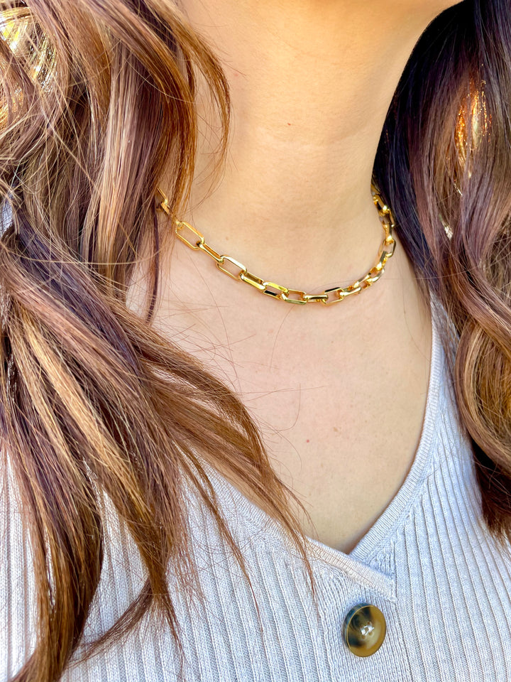 olivia le model wearing linked up necklace chain with a v neck sweater dress showcasing the rectangular links on the chain
