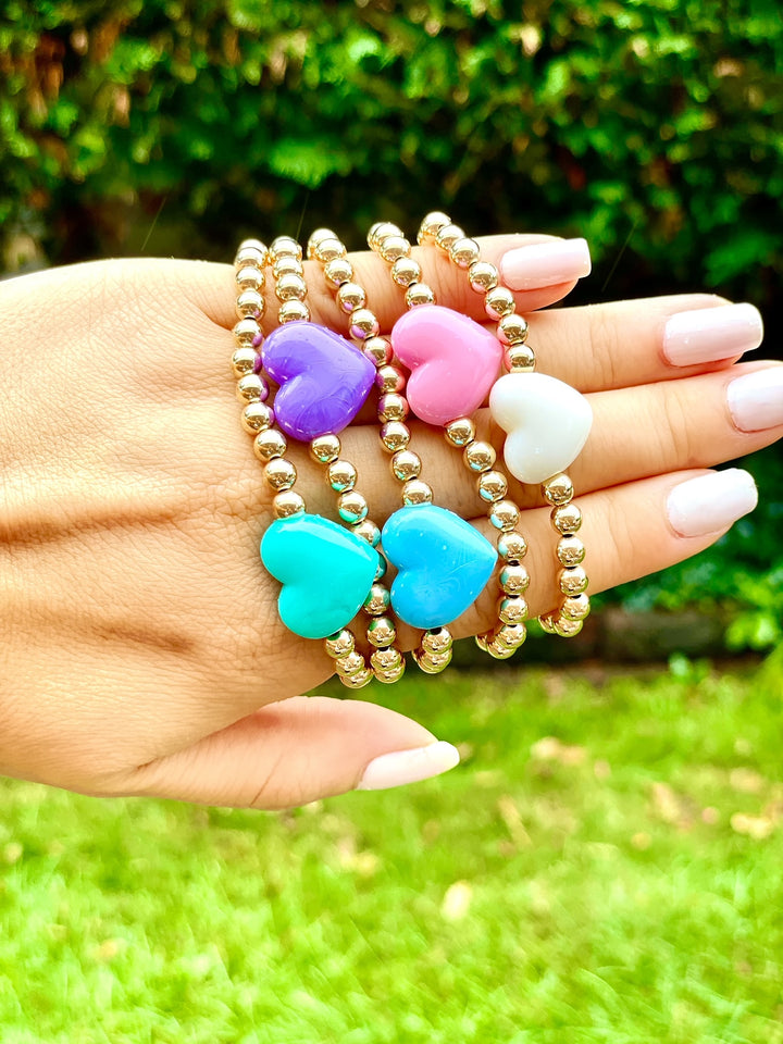 Olivia le love heart bracelet shown in all 5 colors of ivory pink purple teal and aqua on models hand details of 5mm gold filled beads with the puff heart charms 