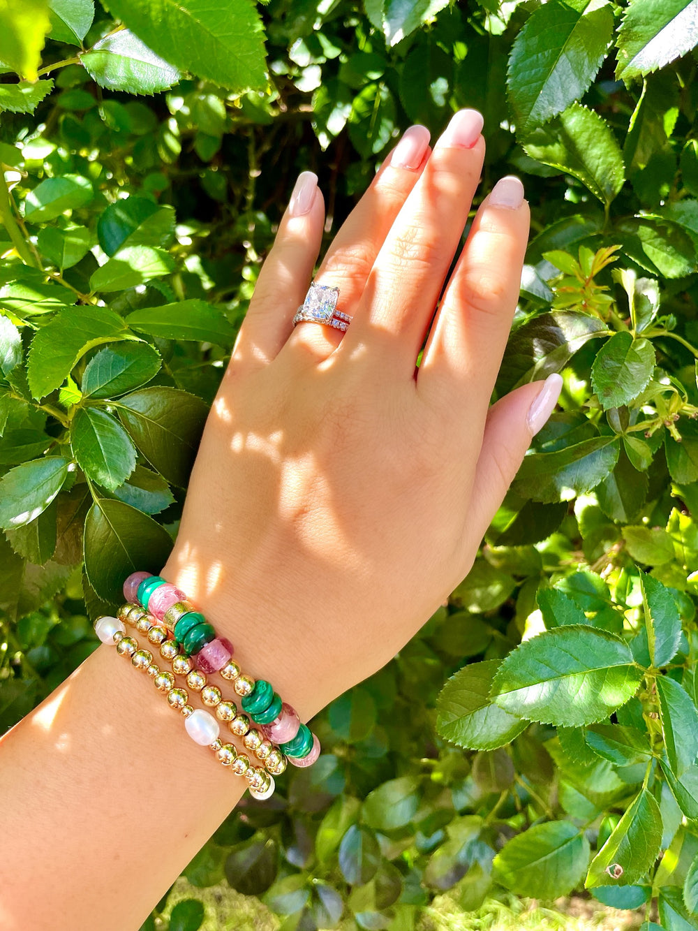 olivia le malachite mixed glass beaded bracelet shown on models hand bracelet has green malachite stones strung with pink glass beads and round gold beads