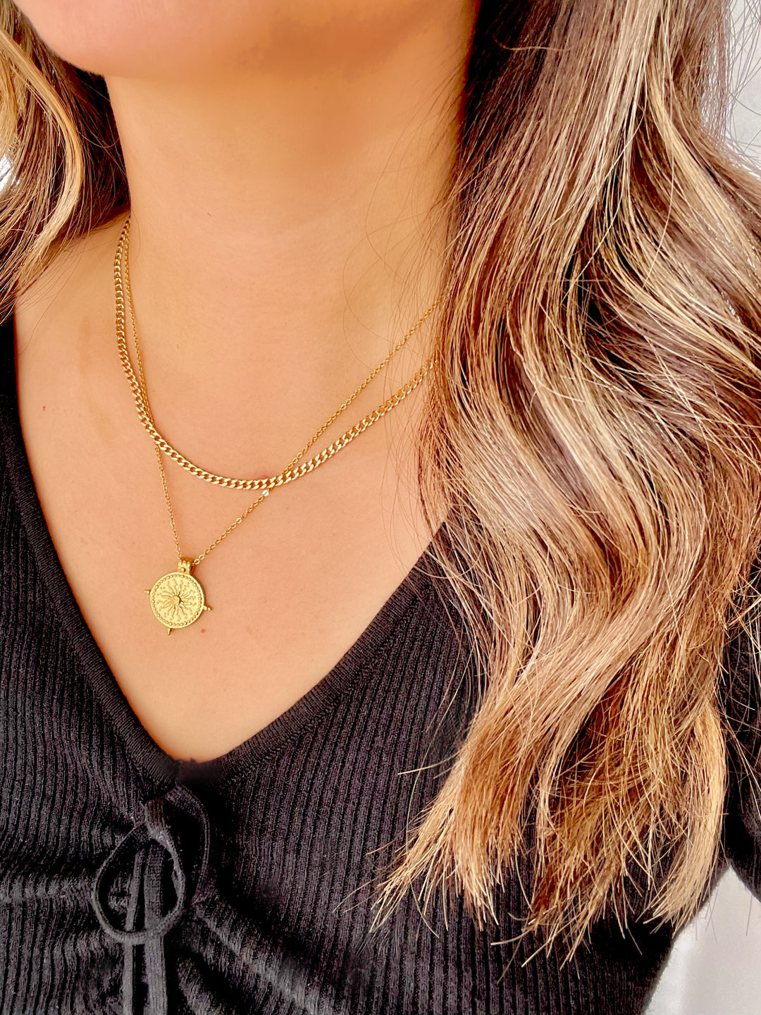 Model wearing layered necklaces to show the compass necklace