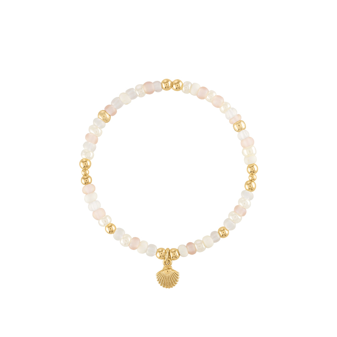 Olivia le shimmer bead bracelet shown with soft pastel pink and ivory beads mixed with gold beads and a gold shell charm on a stretch bracelet