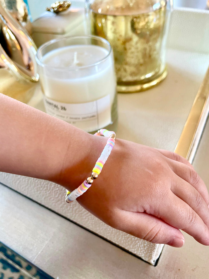 pastel polymer clay beaded stretch bracelet with mother of pearl beads and gold filled beads on a cihlds hand for model image showing bracelet